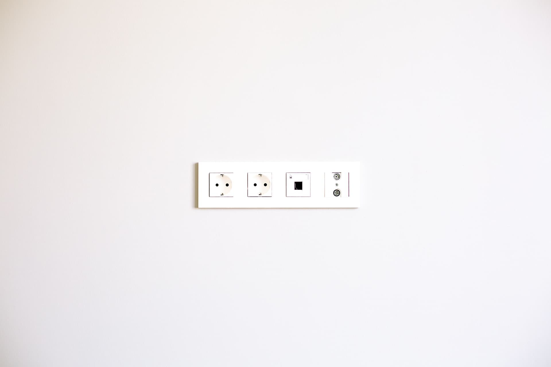 A row of wall outlets set into a plain white wall